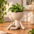 Matera Hombrecito Sentado 3D color arena con planta en un escritorio de madera