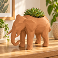Porta maceta con forma de elefante low-poly en color terracota, ambientado sobre una mesa con una suculenta